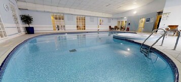 Una piscina interior con agua cristalina, una escalera de piscina y suelo de baldosas.