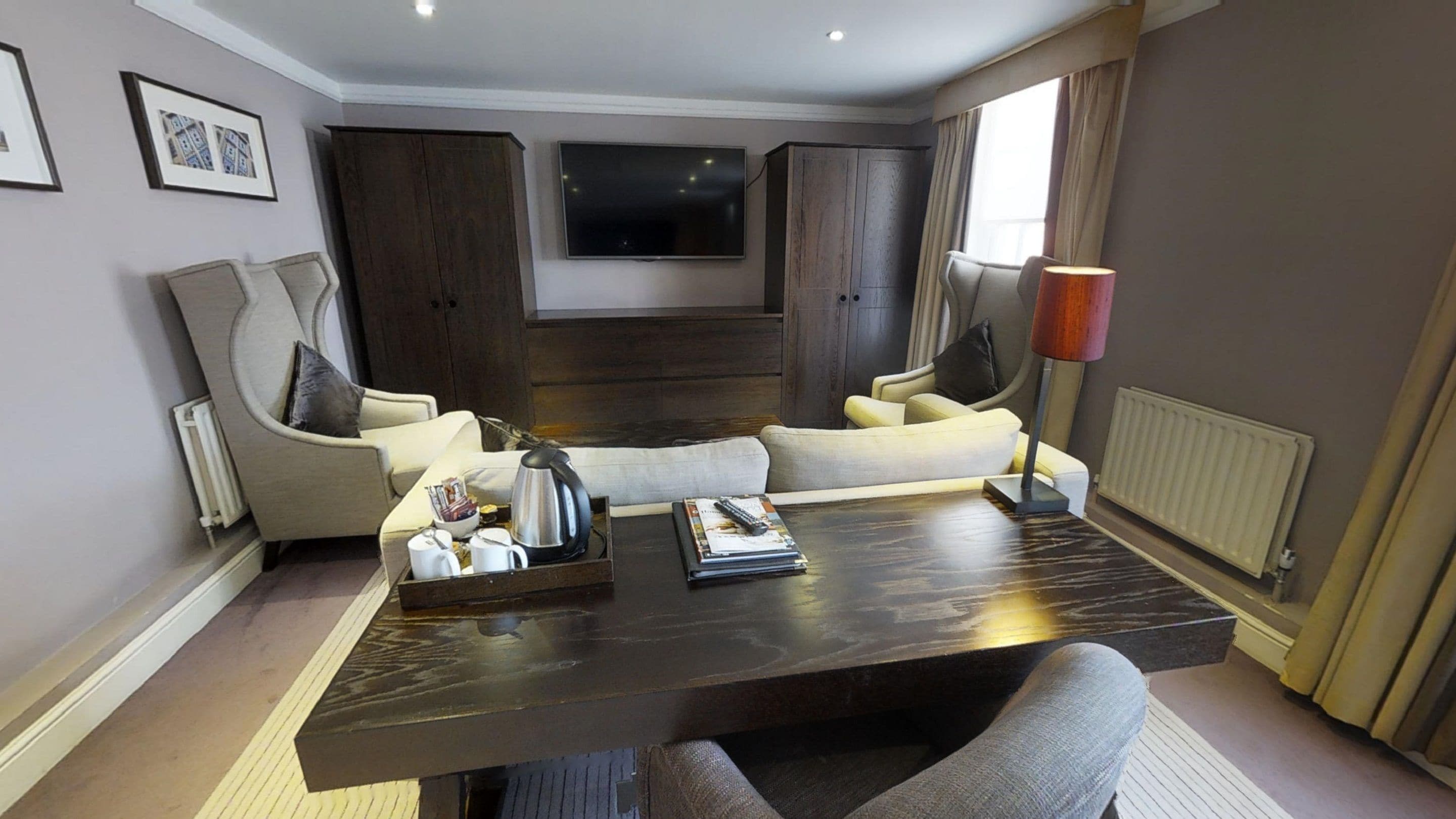 A modern living room with a dark wood coffee table, two sofas, a TV, and a radiator.