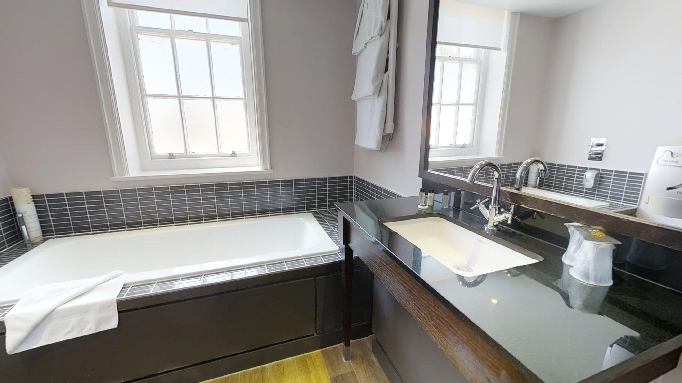 Un baño moderno con bañera, lavabo y un espejo grande.