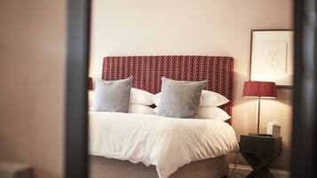 A neatly made bed with a patterned headboard, a bedside lamp, and a framed picture on the wall.