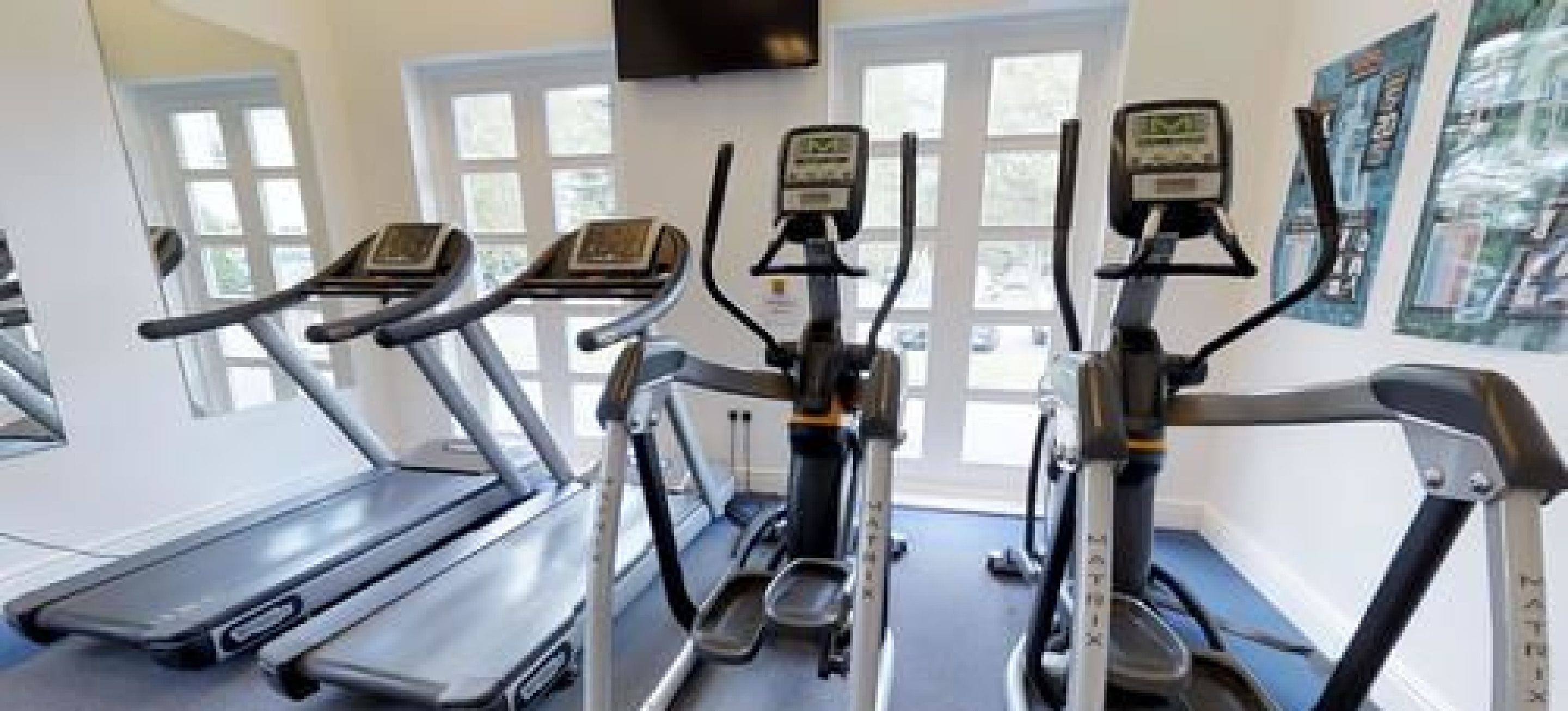 Un gimnasio con cintas de correr y máquinas elípticas.