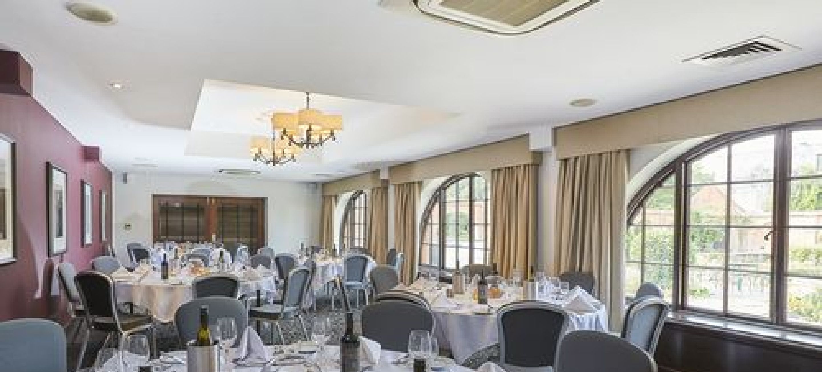 Een vergaderzaal met ronde tafels, stoelen en een kroonluchter.
