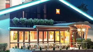 A hotel with a sign reading 'ibis HOTEL,' outdoor seating, and a stone wall. - ibis Pontarlier (Pontarlier)