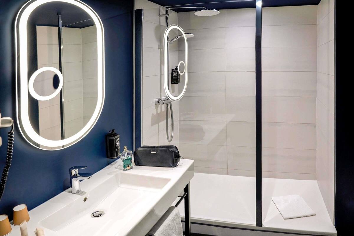 A modern bathroom with a large mirror, a shower, and a vanity.