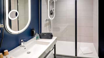 Une salle de bain moderne avec un grand miroir, une douche et un meuble-lavabo.