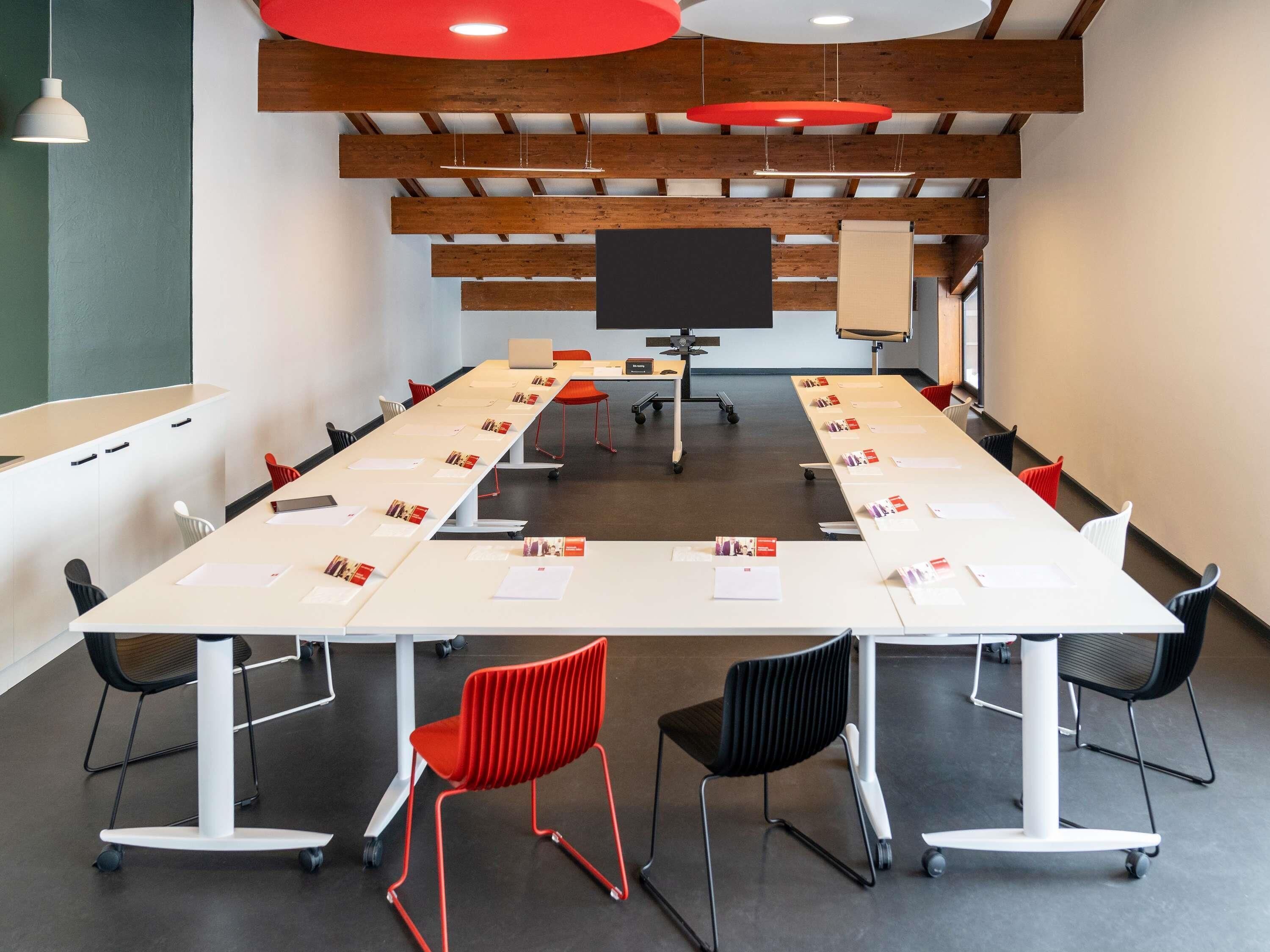 A conference room with a long table, chairs, a projector screen, and a whiteboard.