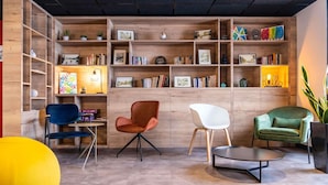 A modern interior with wooden shelving, books, and three chairs. - ibis Pontarlier (Pontarlier)