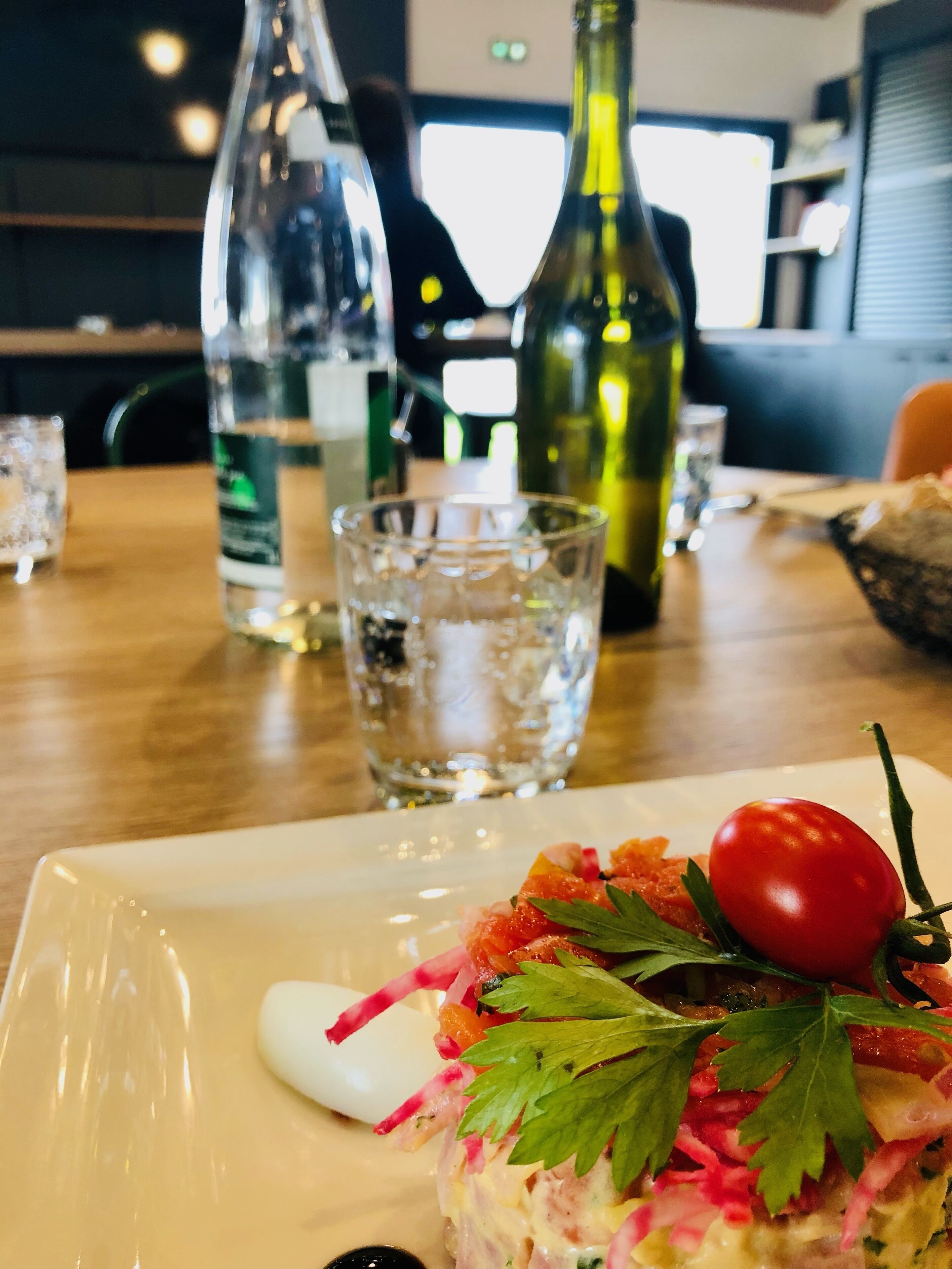 Ein Esstisch mit einer Speisenplatte, einem Glas Wasser und zwei Wasserflaschen.