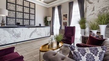 A modern living room with a marble reception desk, plush seating, and decorative plants.