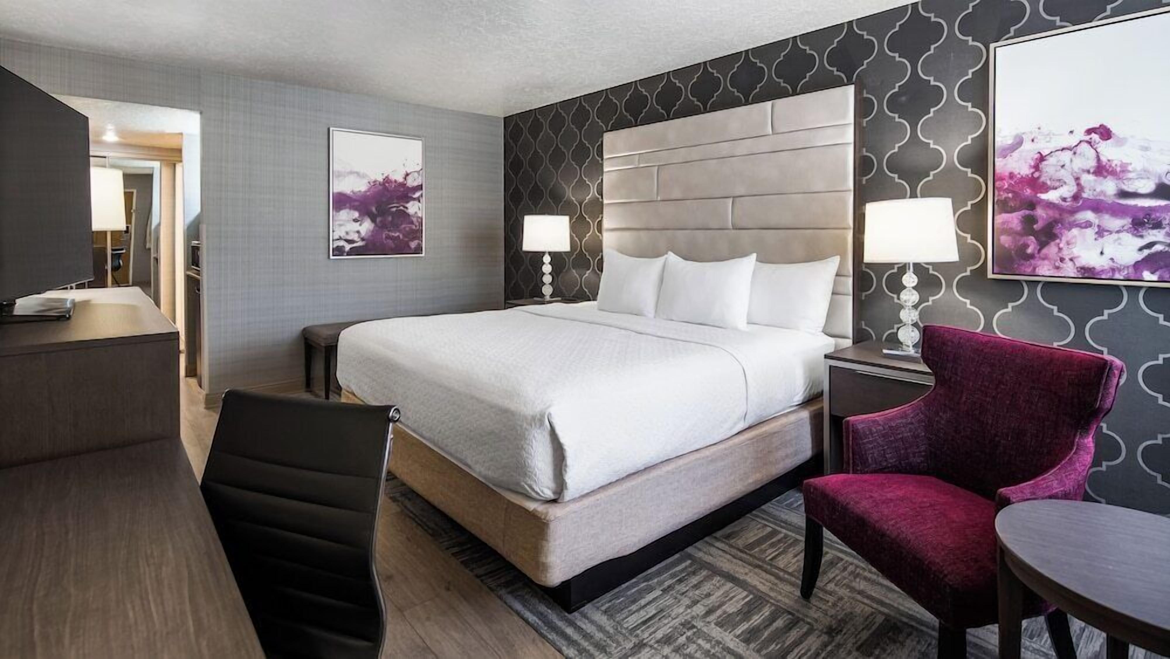 Une chambre d’hôtel équipée d’un lit, d’un bureau, d’une chaise et de deux lampes fixées au mur.