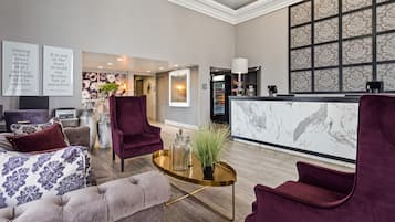 Un vestíbulo moderno con un mostrador de recepción, asientos cómodos y arte decorativo en la pared.