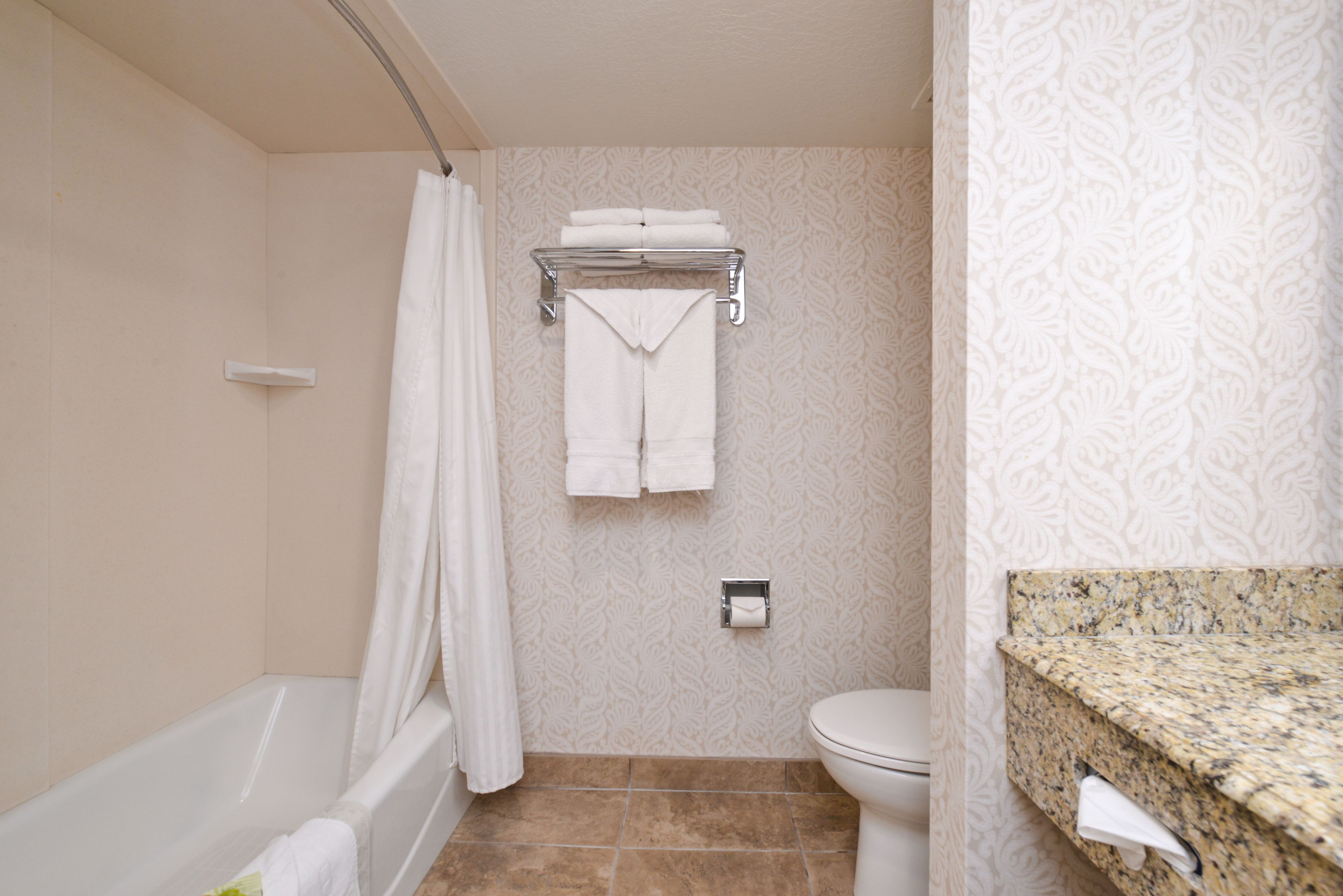 A bathroom with a bathtub, toilet, and towel rack.
