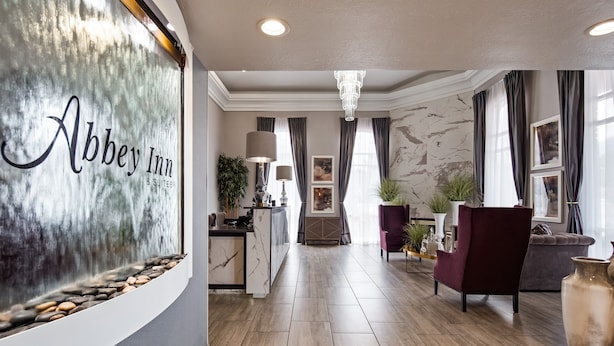 A hotel lobby with a marble reception desk, a chandelier, and a seating area with armchairs and a sofa.