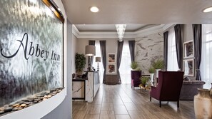 A hotel lobby with a marble reception desk, a chandelier, and a seating area with armchairs and a sofa. - Abbey Inn (Cedar City)
