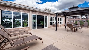 A covered patio area with wicker lounge chairs, a table, and a pergola.