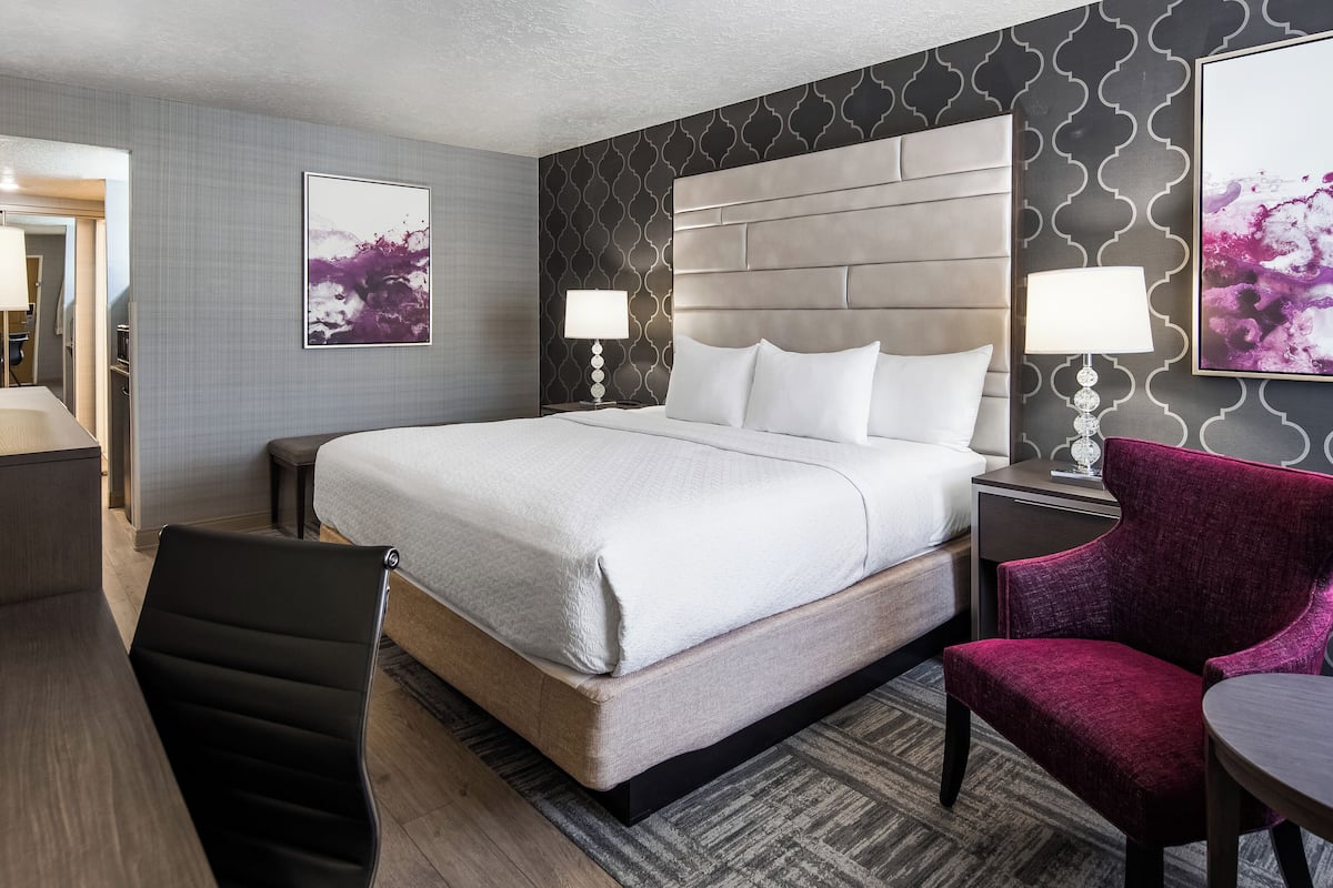 Una habitación de hotel con una cama grande, un escritorio, una silla y una pequeña mesa.