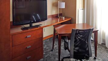 Une chambre d’hôtel avec un bureau en bois, une télévision, une lampe et une chaise.