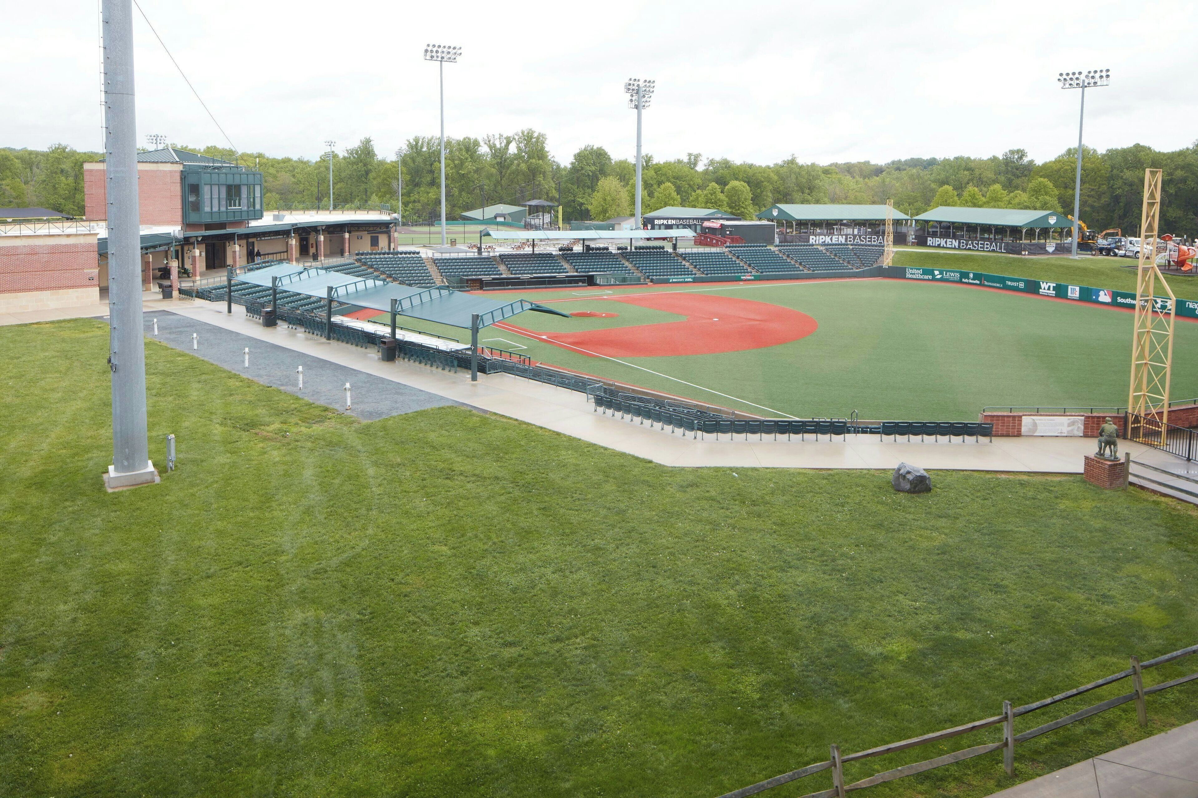 Un estadio de béisbol con césped verde, zonas de asientos y un marcador.