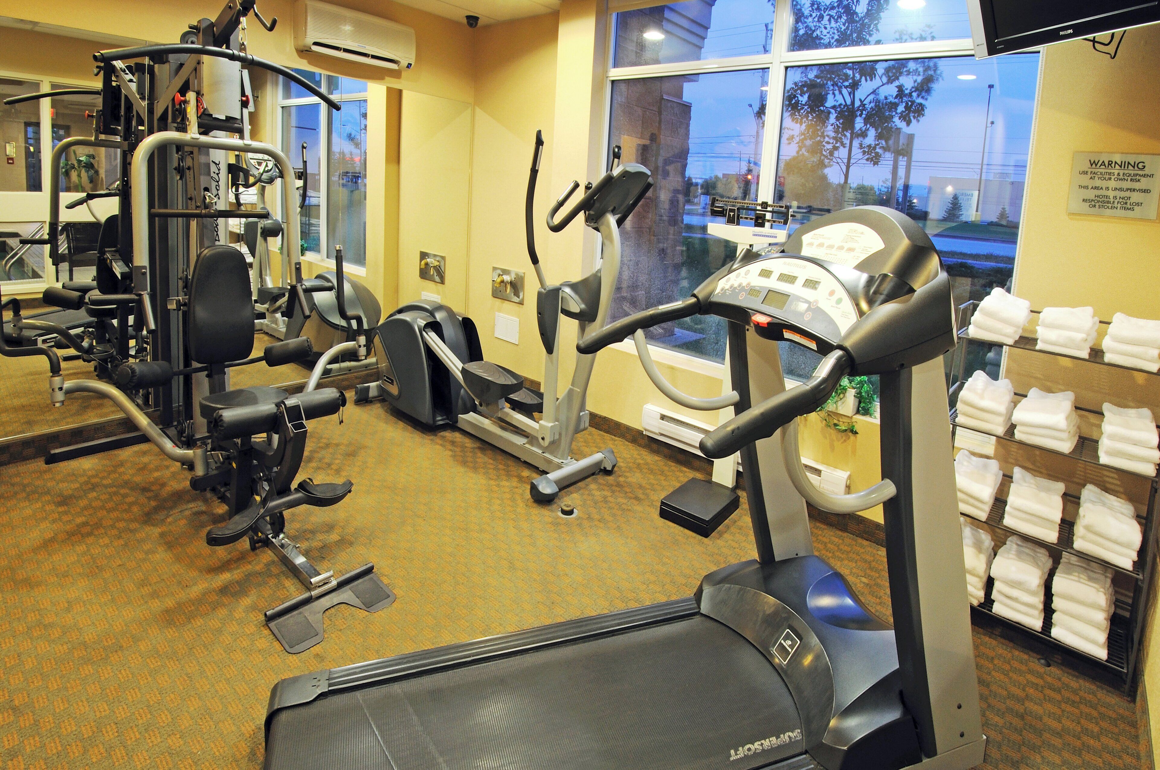 Une salle de sport d’hôtel équipée de divers appareils d’exercice, notamment des tapis de course et des appareils de musculation.