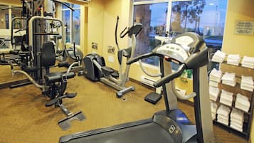 Une salle de sport d’hôtel équipée de divers appareils d’exercice, notamment des tapis de course et des appareils de musculation.