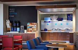 A modern cafe with seating, a coffee station, and a breakfast bar.