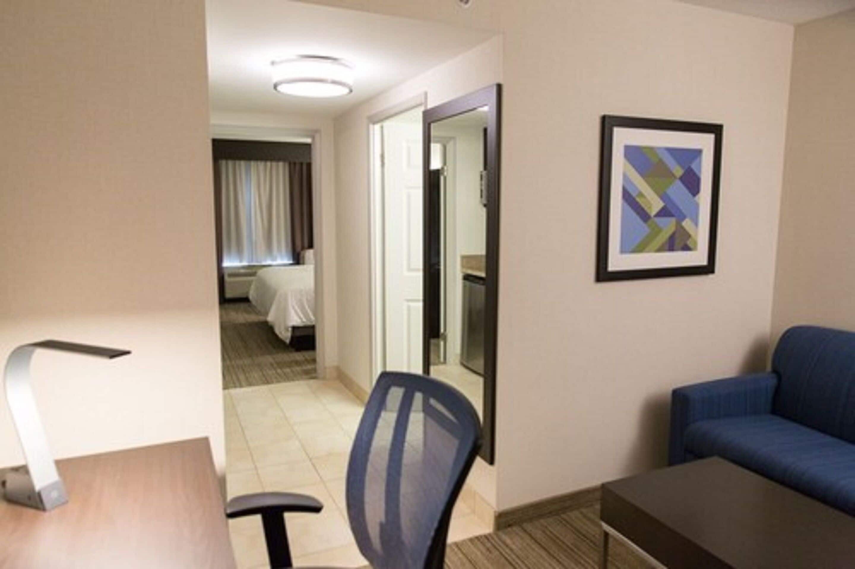 Hotellihuoneessa on sänky, työpöytä, tuoli, sohva ja seinällä oleva kehystetty taulu.