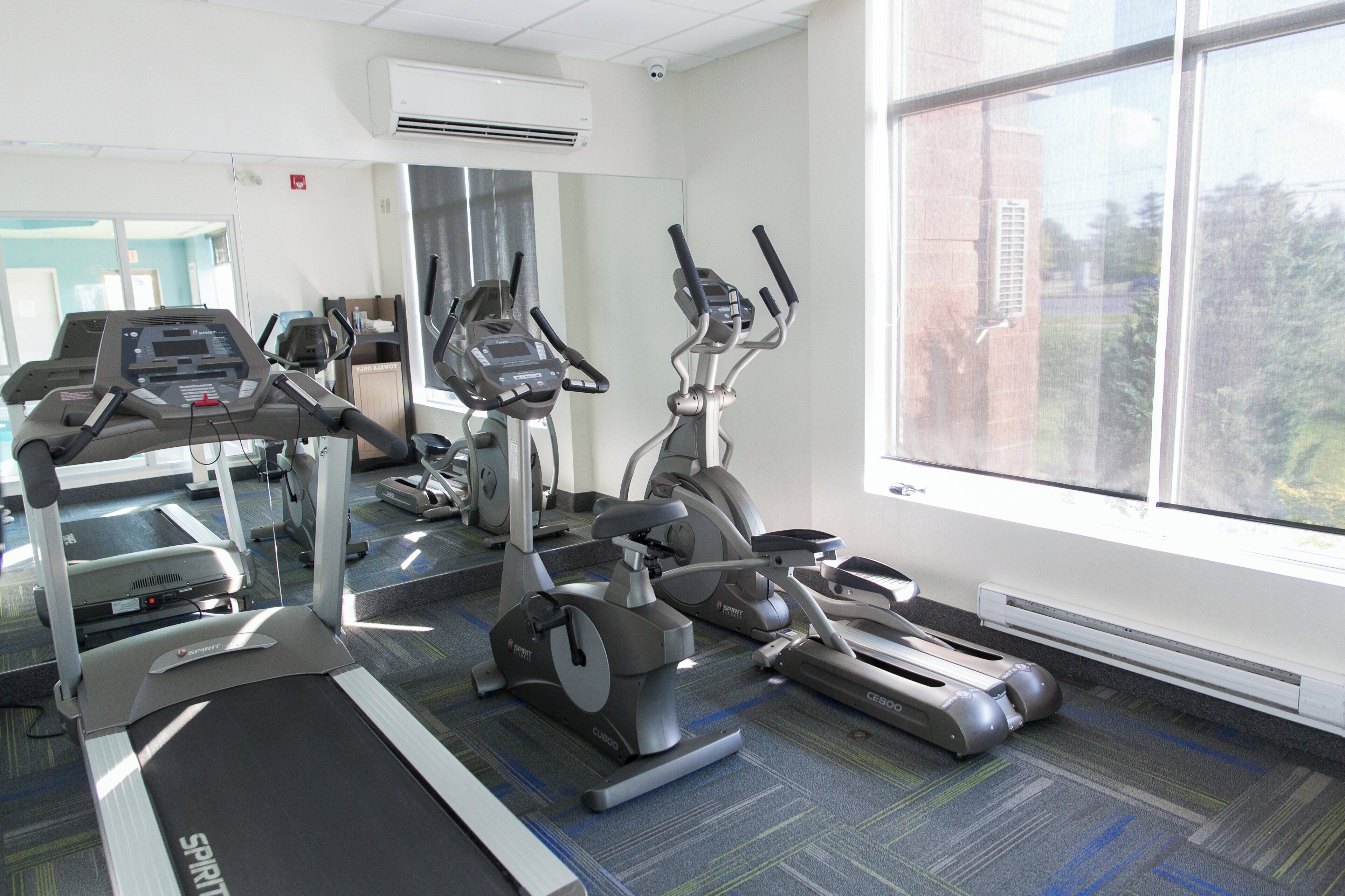 Un gimnasio con cintas de correr, elípticas y bicicletas estáticas.
