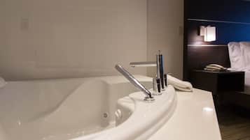 Un bagno moderno con una grande vasca, un lavabo e un comodino con una lampada.