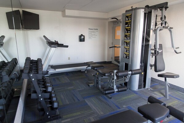 A fitness center with cardio equipment, weight machines, and a wall-mounted television.