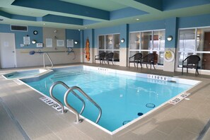 Una piscina interior con agua cristalina, marcas de profundidad y señales de seguridad.