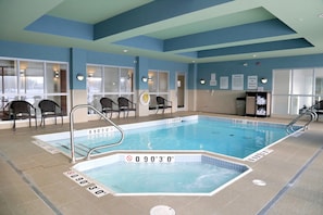 An indoor swimming pool with a depth of 9 feet 3 inches, surrounded by chairs and a lifeguard station.