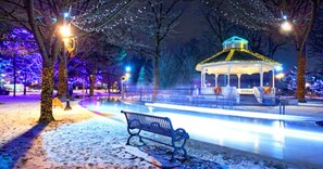 A gazebo with a snow-covered ground and benches, surrounded by trees and illuminated by string lights. - Holiday Inn Express & Suites Brampton by IHG (Brampton)
