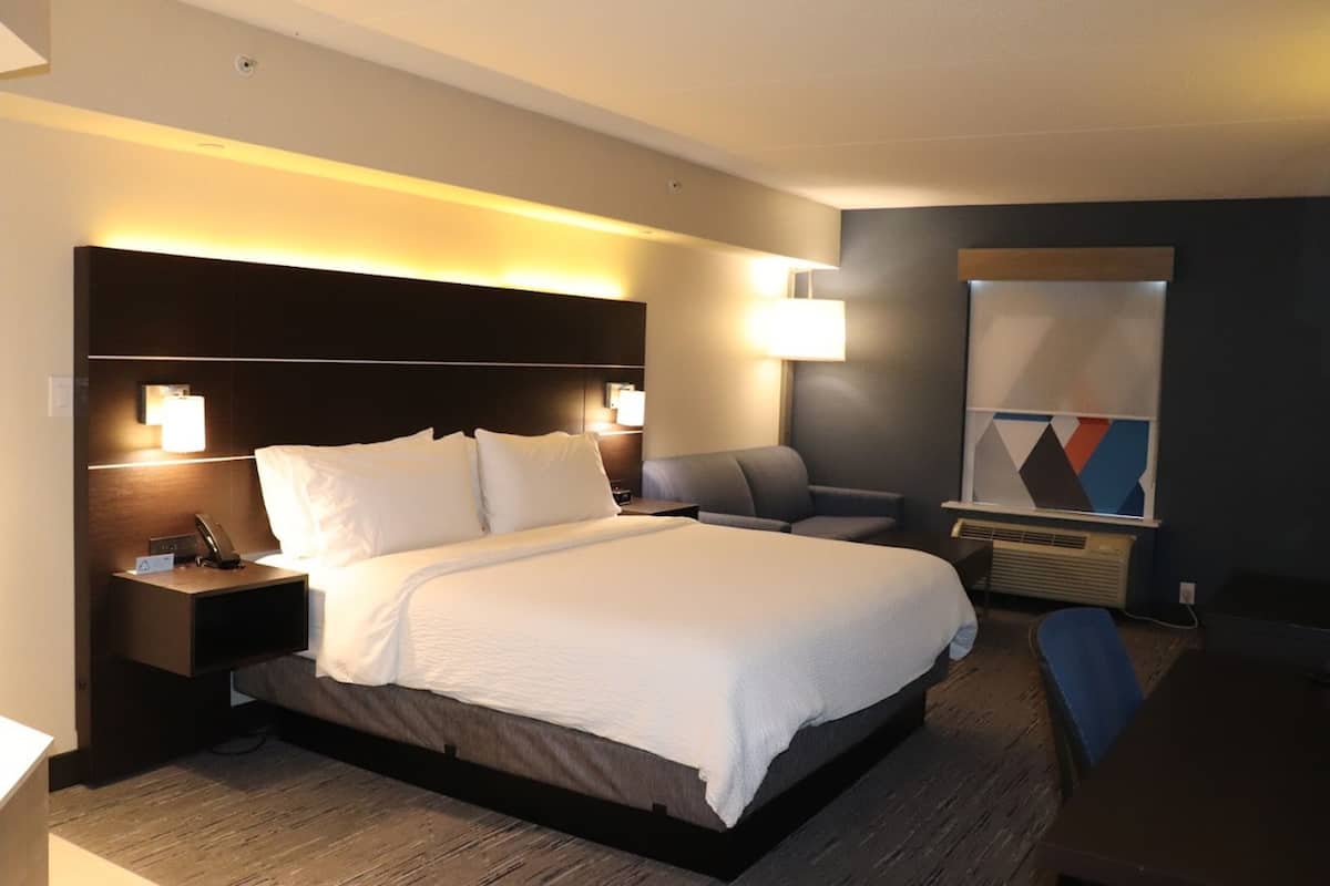 A modern hotel room with a large bed, bedside tables with lamps, a desk, and a chair.
