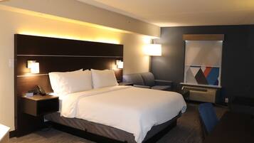 A modern hotel room with a large bed, bedside tables with lamps, a desk, and a chair.
