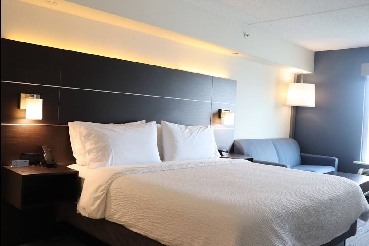 A modern hotel room with a large bed, bedside lamps, a desk, and a chair.