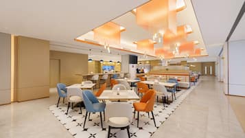 A modern restaurant with a long counter, multiple seating areas, and pendant lighting.