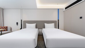 A hotel room with two single beds, a small table with a chair, a telephone, and a wall-mounted control panel. - Holiday Inn Express Dalian City Centre by IHG (Dalian)