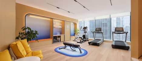 Un gimnasio moderno con equipo de ejercicio, una banca y un ventanal grande.