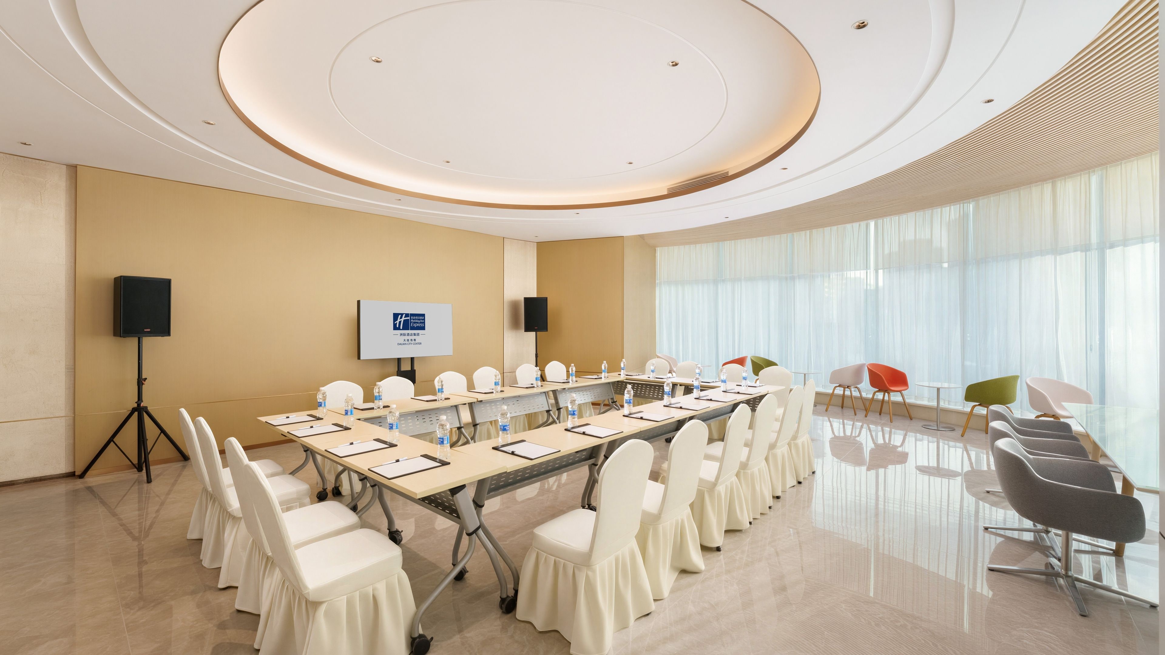A conference room with a long table, chairs, a speaker, and a screen.