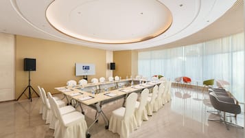 A conference room with a long table, chairs, a speaker, and a screen.