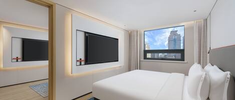 A modern hotel room with a large bed, two wall-mounted TVs, a window with a city view, and a patterned rug.