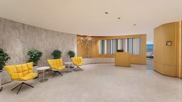 A modern lobby with a marble floor, yellow chairs, a reception desk, and a large window with colorful curtains.