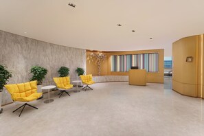 A modern lobby with a marble floor, yellow chairs, a reception desk, and a large window with colorful curtains. - Holiday Inn Express Dalian City Centre by IHG (Dalian)