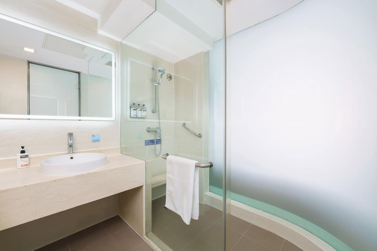 A modern bathroom with a glass-enclosed shower, a sink with a mirror, and a towel rack.