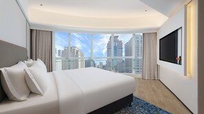 A modern hotel room with a large bed, a TV mounted on the wall, and a city view through large windows. - Holiday Inn Express Dalian City Centre by IHG (Dalian)