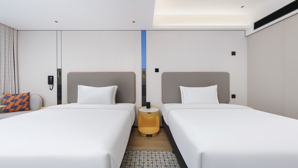 A hotel room with two beds, a bedside table, a phone, and a small window. - Holiday Inn Express Dalian City Centre by IHG (Dalian)
