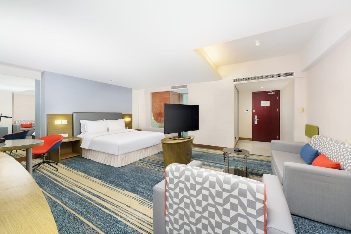A hotel room with a bed, a TV, a desk, and a sofa.