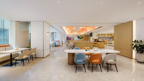 A modern dining area with a central island, multiple seating options, and a kitchen in the background. - Holiday Inn Express Dalian City Centre by IHG (Dalian)