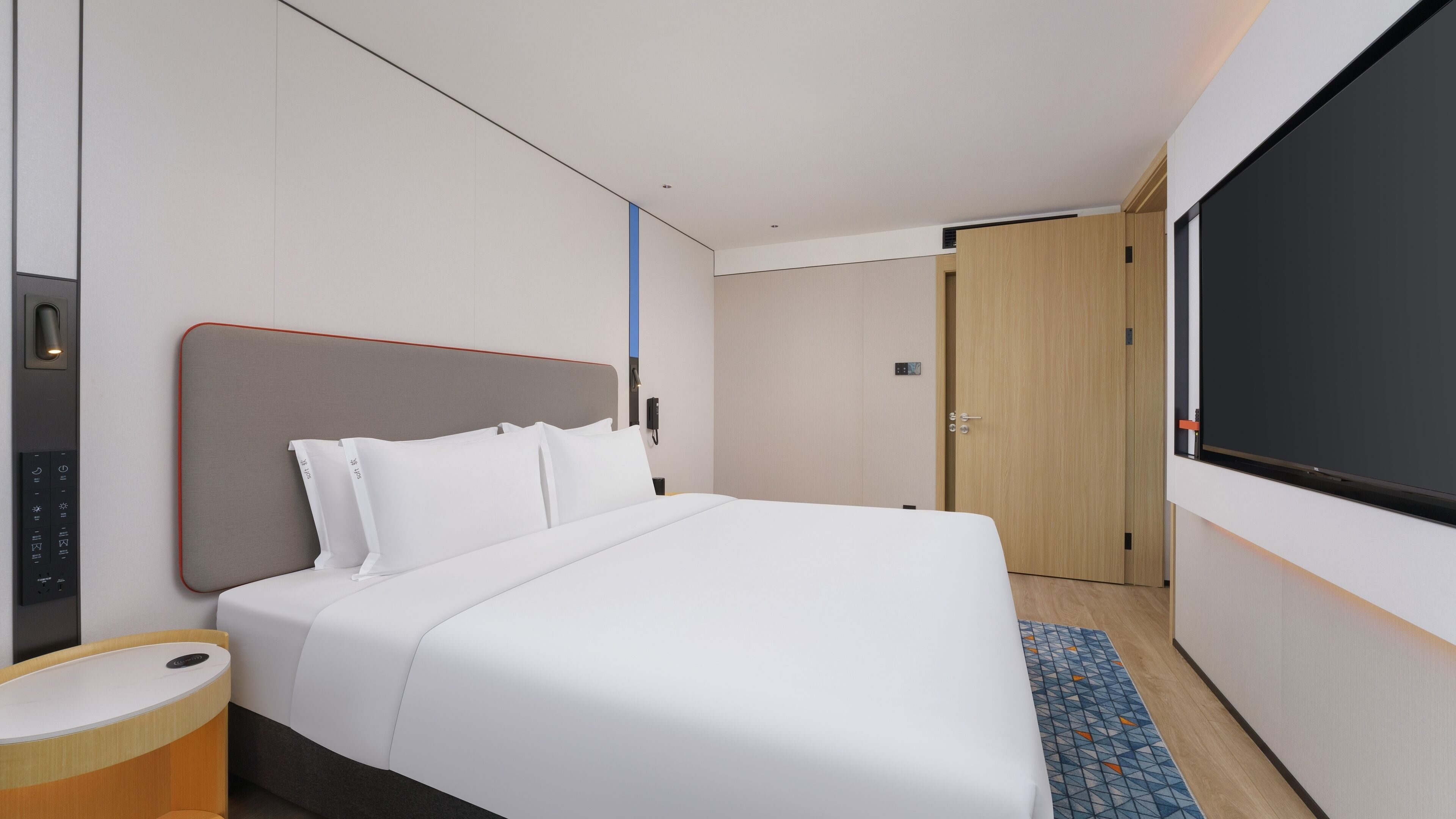 Una habitación de hotel con cama, mesita de noche, televisor y puerta.