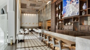 Een moderne hotellobby met een lange receptiebalie, een zithoek en decoratieve wandkunst.